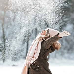 Woman smiling and throwing snow into the air in a joyful way